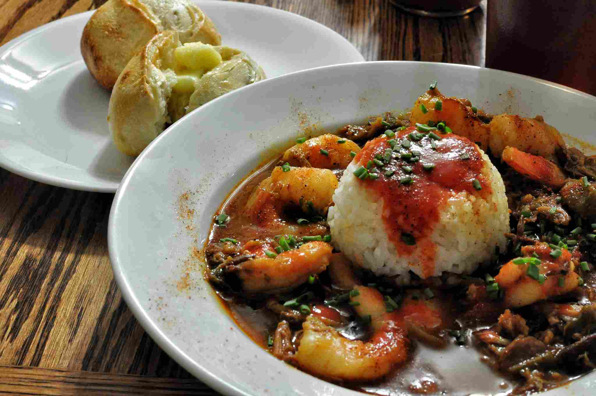 Dark Seafood Gumbo With Rice and Buttered Bread Rolls